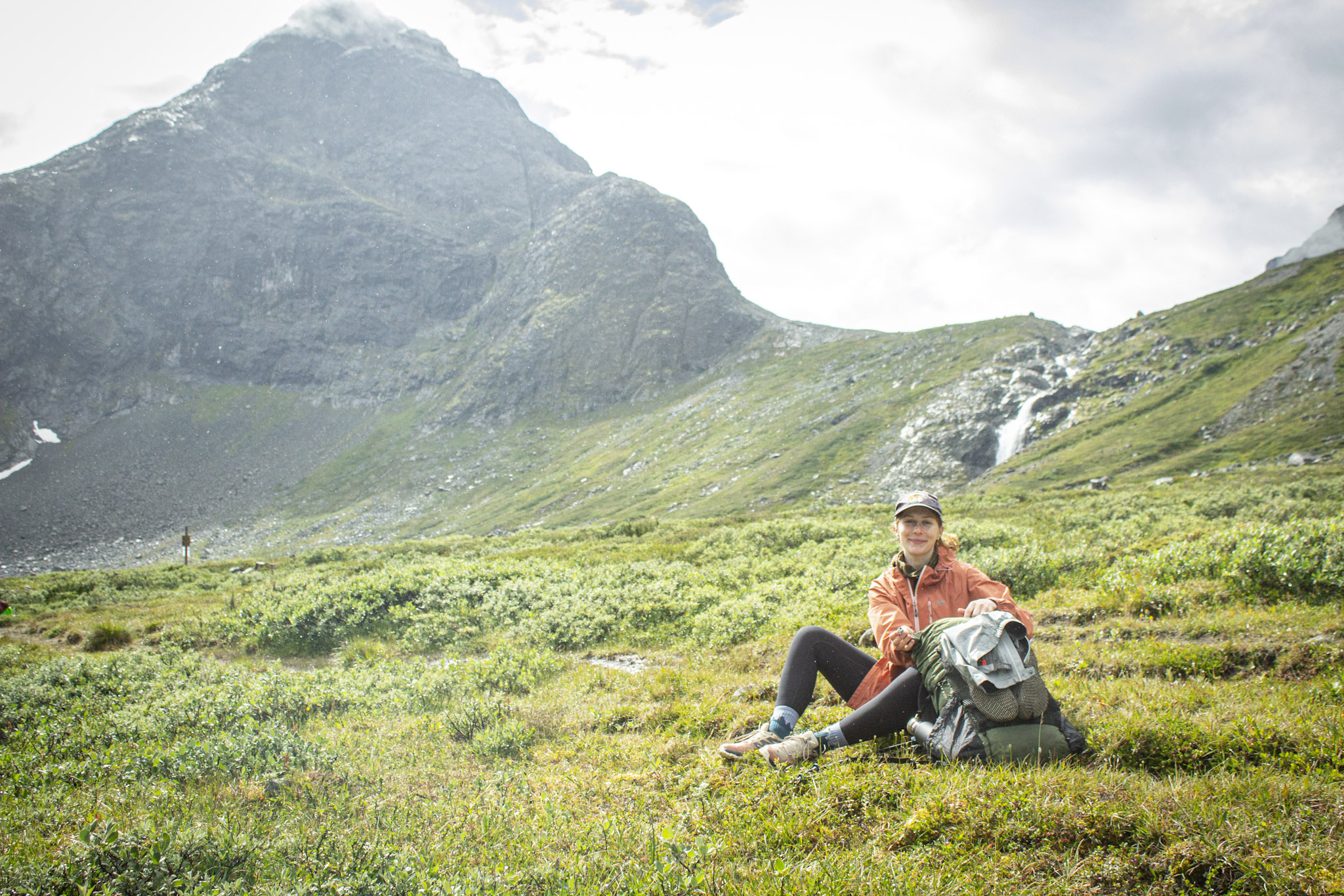 Mary Wilson seated on a grassy slope in the mountains